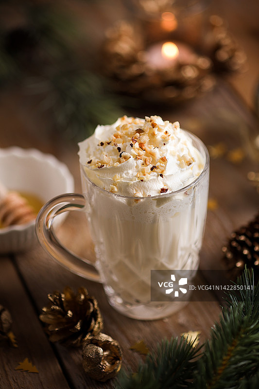 圣诞热巧克力蛋奶酒，玻璃杯装，顶部有搅打奶油和坚果图片素材