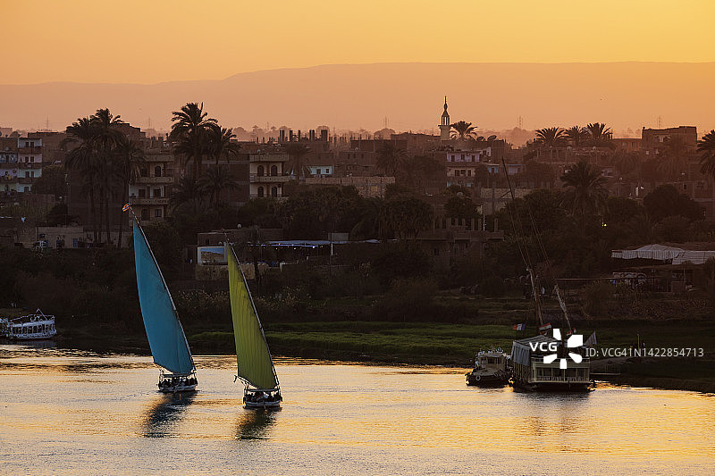 尼罗河日落时分的三角帆船和船只图片素材