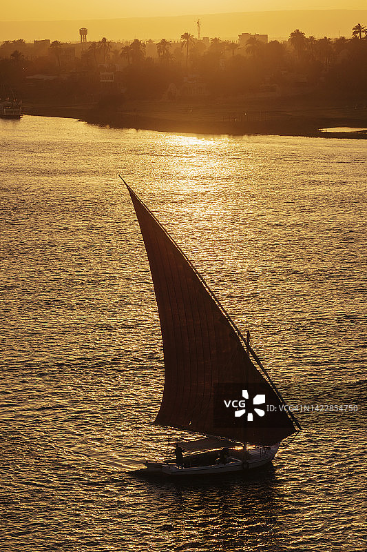 尼罗河日落时分的三角帆船和船只图片素材