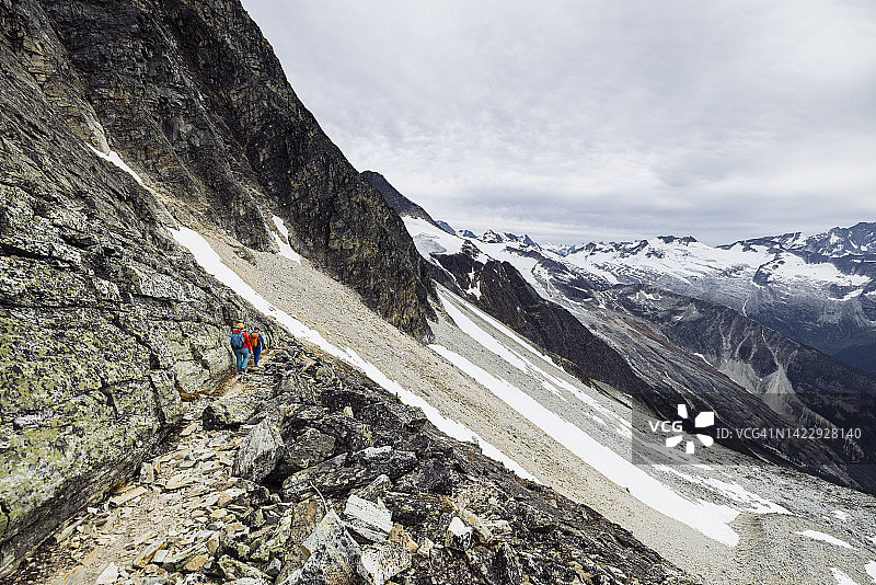 两人在不列颠哥伦比亚省罗杰斯Pass附近的高山小径上徒步旅行图片素材
