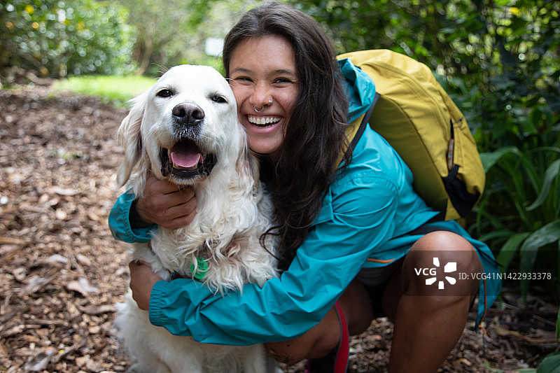 女人背包在自然中拥抱小狗图片素材