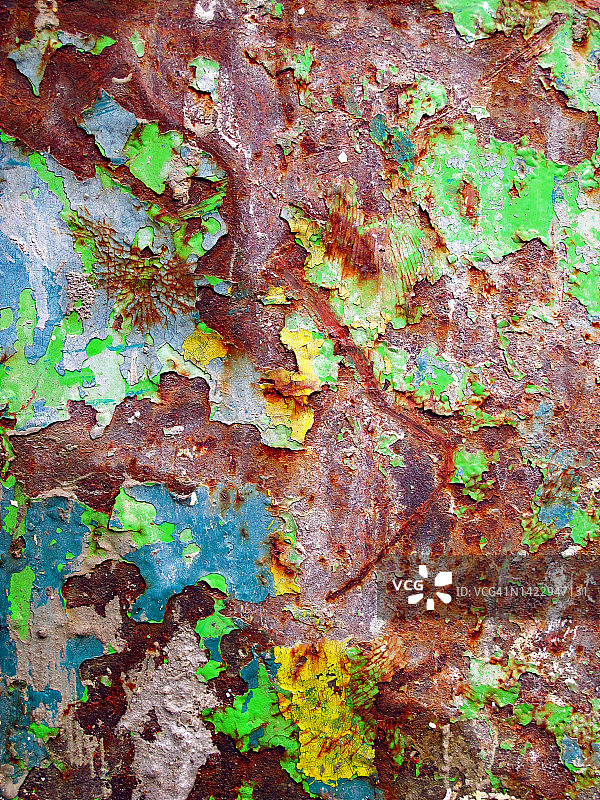 巴黎锈迹斑斑的金属板上的黄色、蓝色、绿色油漆层图片素材