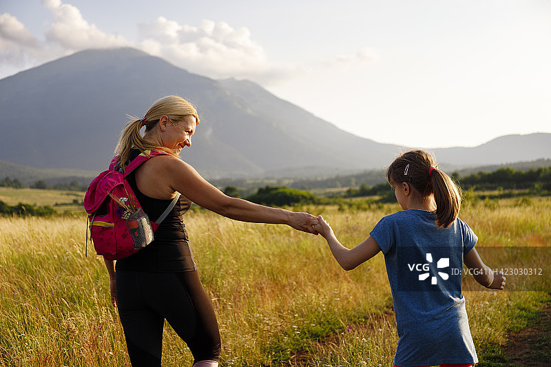 夕阳下在田野里徒步的母女图片素材