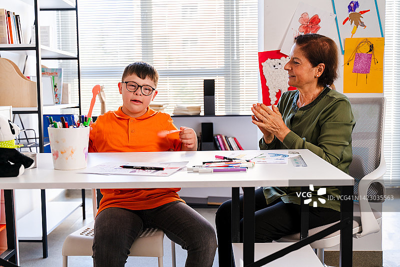 患有唐氏综合症的男孩在指导员的指导下演奏音乐图片素材