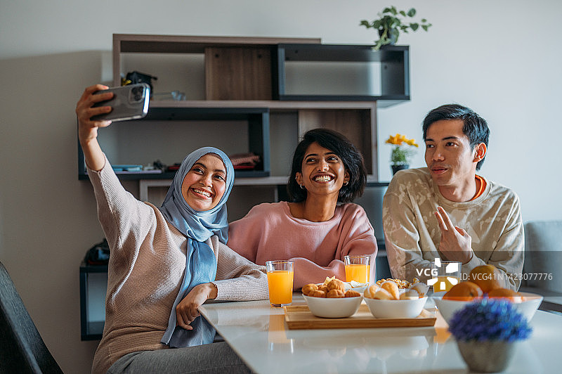多民族朋友在家自拍，三位亚洲年轻朋友坐在一起自拍图片素材