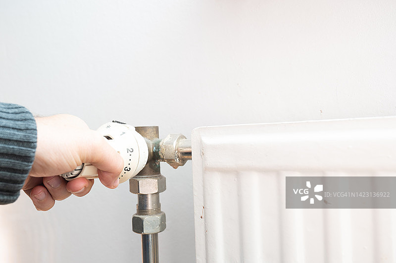 调节散热器温度的人（能源价格上涨）图片素材