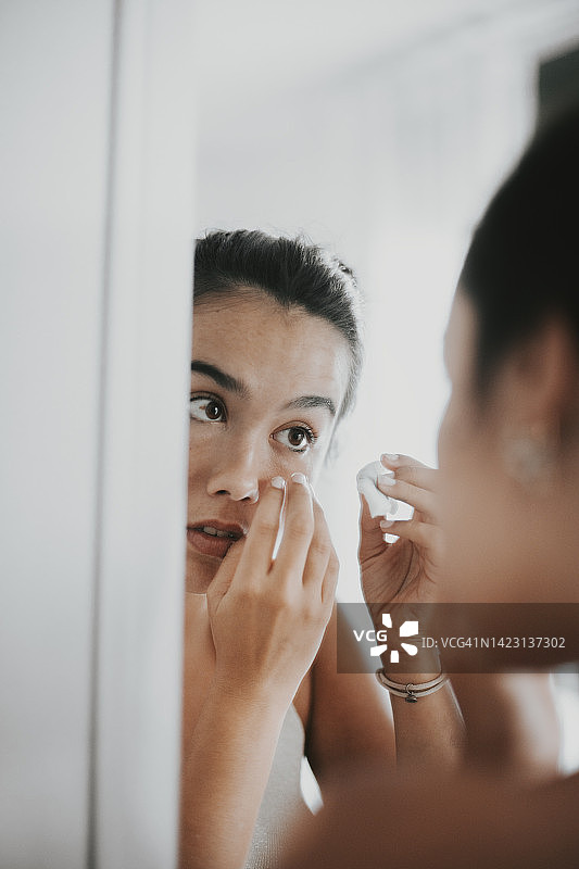 用棉球清洁眼睛的年轻女子肖像图片素材
