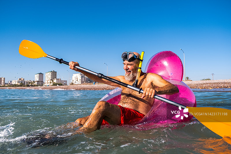 快乐健康的乐龄老人在阳光明媚的日子里划着独木舟图片素材