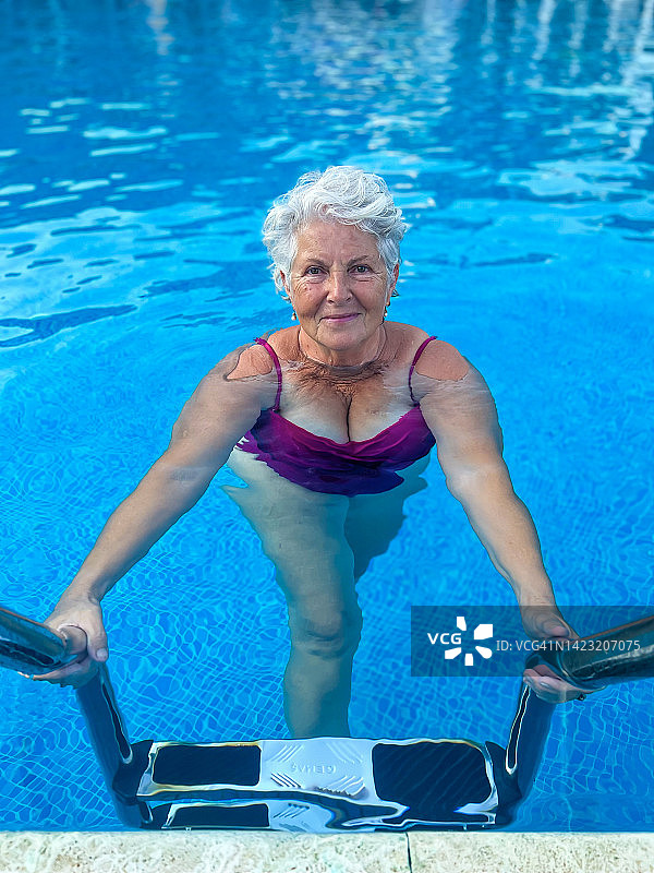 在游泳池里微笑看着镜头的年长美丽女性图片素材