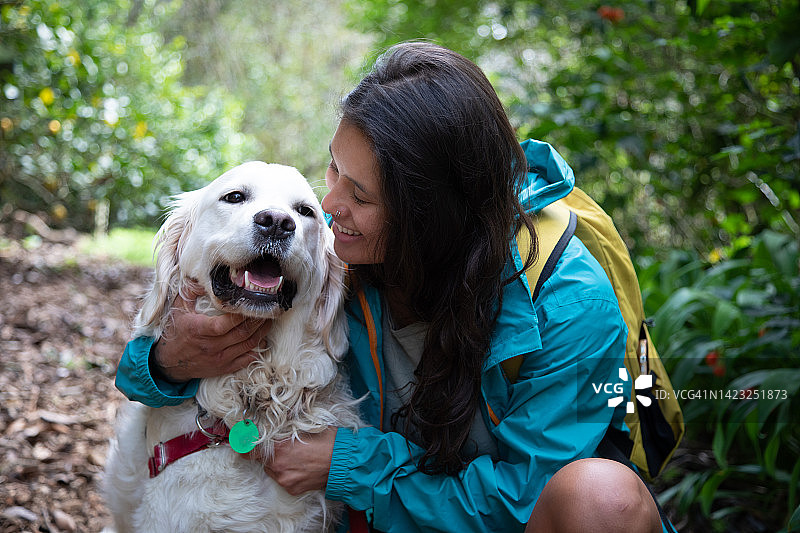女人背包在自然中拥抱小狗图片素材