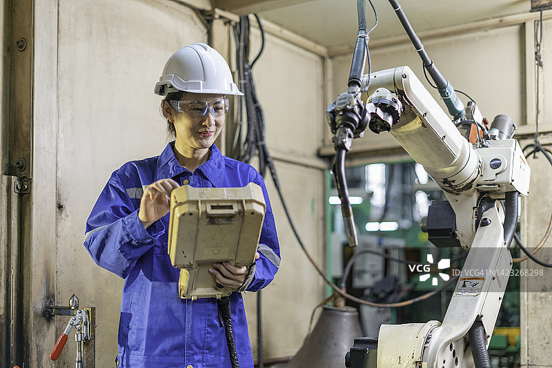 工程师在工厂使用机器人手臂控制面板图片素材