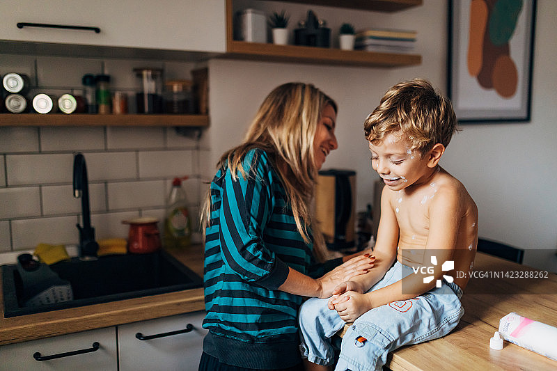 微笑的母亲照顾着患有水痘的可爱小儿子图片素材