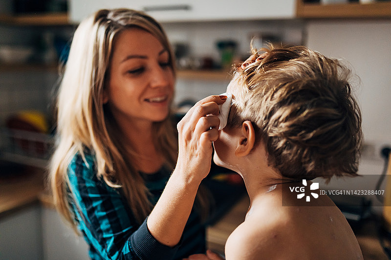 笑着给儿子涂水痘药的母亲半身像图片素材