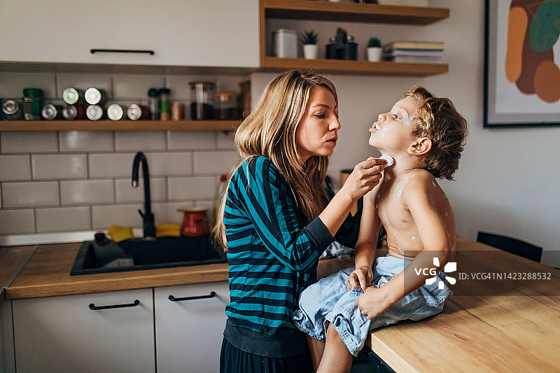 年轻妈妈给儿子脖子上涂抹治疗水痘的药图片素材