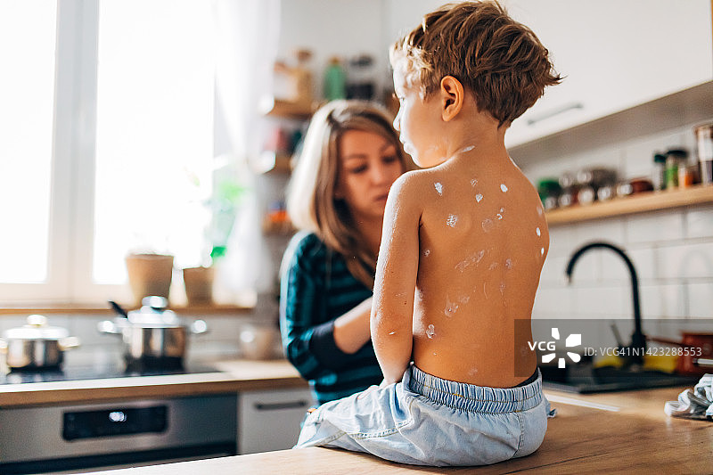 母亲给儿子喂药治疗水痘图片素材