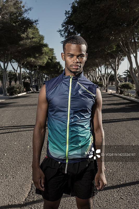 表情严肃的年轻运动员站在空旷的道路上图片素材