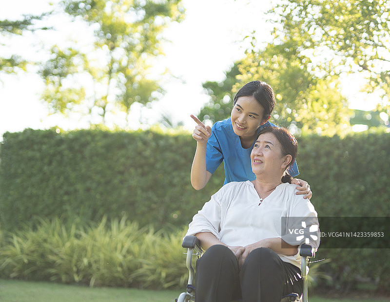 亚洲女护士在家里帮助坐轮椅的女老年患者，传递幸福情感图片素材