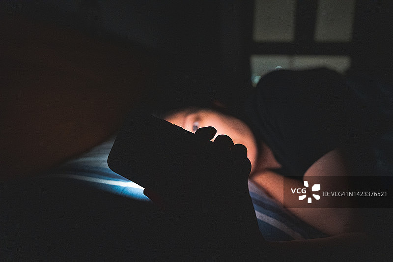 女子夜晚在床上使用手机图片素材