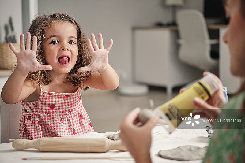小女孩伸出舌头，展示她脏兮兮的手图片素材