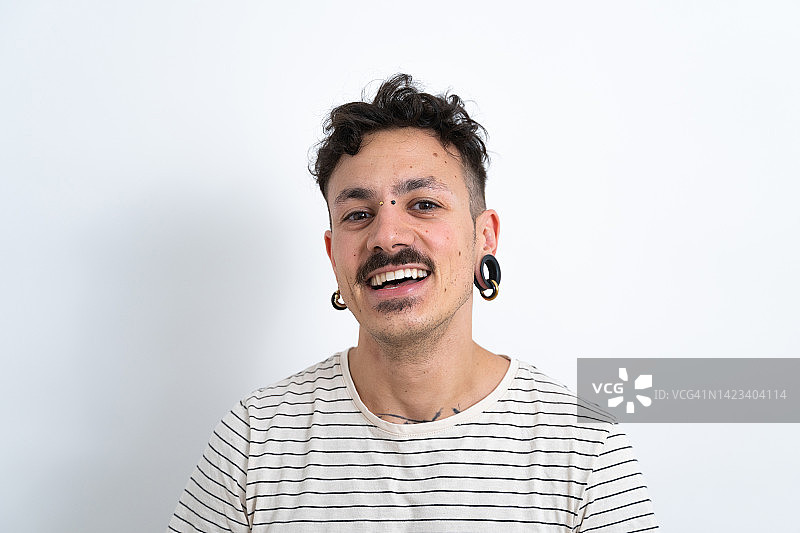 在白色照相馆里微笑并看着镜头的男士图片素材