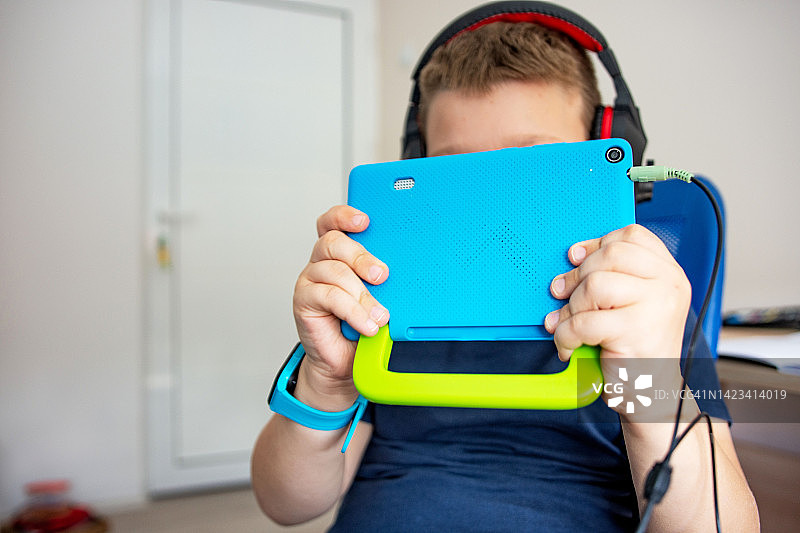 戴耳机玩平板电脑的男孩图片素材