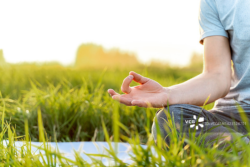 在日落时分的田野里做瑜伽的年轻人，夏季健康概念图片素材