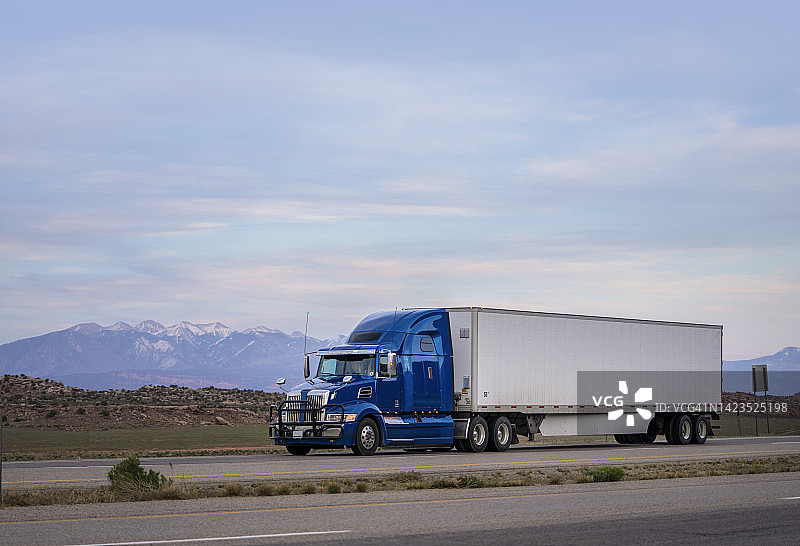 黄昏时分运输商品的蓝白色半挂卡车图片素材