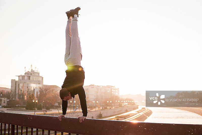 男人在户外日落时单臂倒立图片素材
