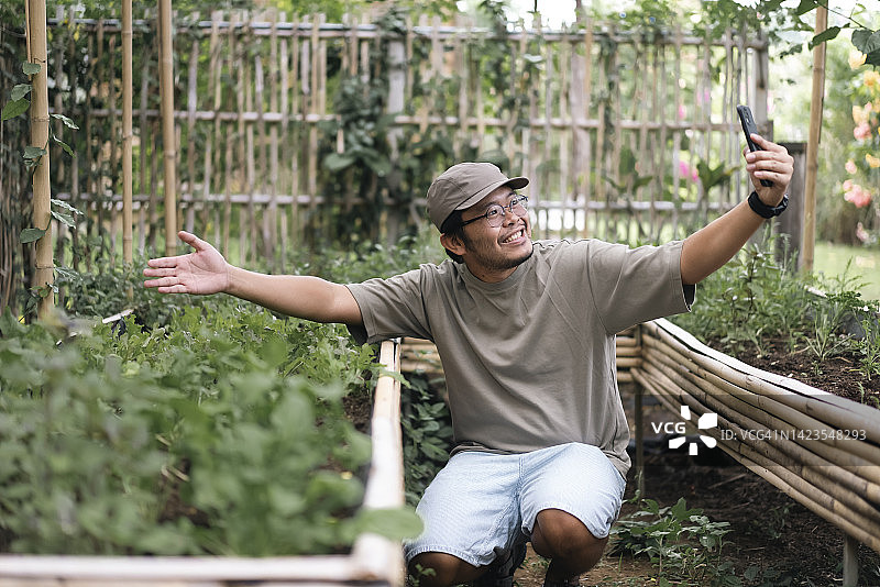 亚裔青年智能农民在家拍摄蔬菜种植视频，实现可持续生活图片素材