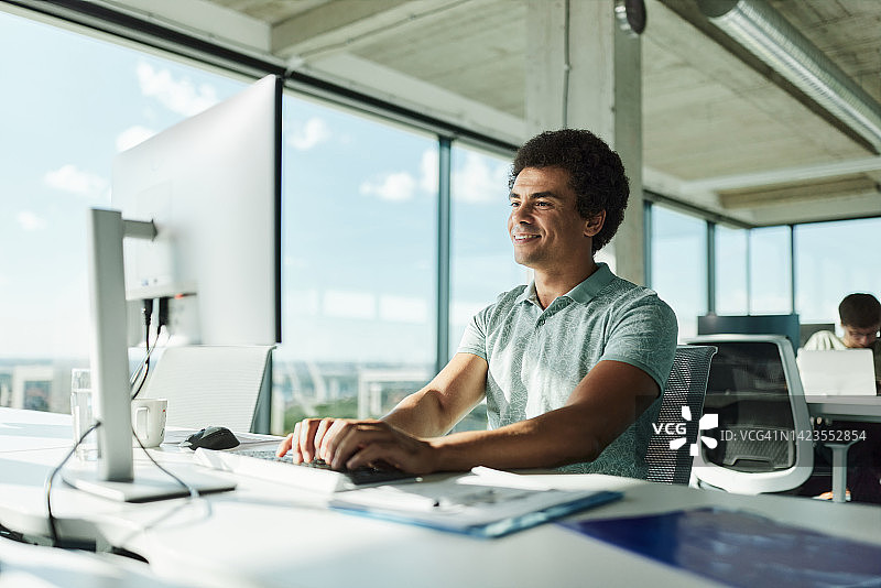 快乐的程序员在办公室使用台式电脑工作图片素材