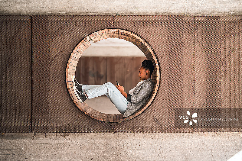 美丽的年轻黑人女性在城市户外用手机发短信图片素材