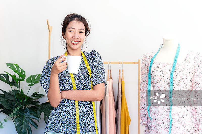 亚洲女设计师在展厅工作后喝咖啡放松，时尚设计师在工作室使用电脑服装设计图片素材