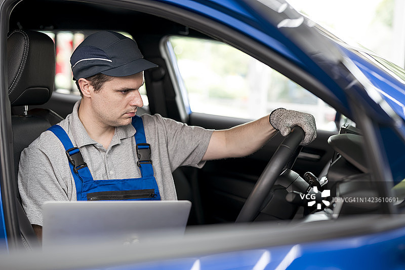 调整方向盘和转向柱的对齐。汽车修理工在车辆维修和诊断中心通过使用诊断软件检查和调整汽车内部方向盘的对齐图片素材