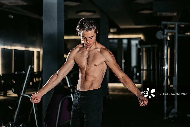 年轻男人在健身房展示肌肉图片素材