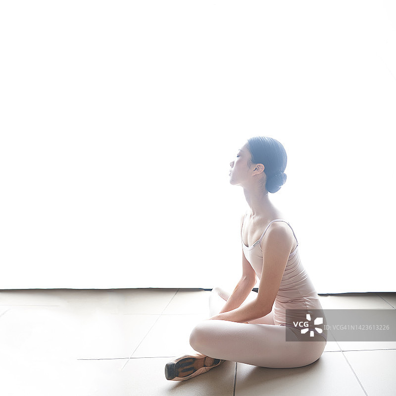 在白色背景中休息并看向远方的日本年轻芭蕾舞演员图片素材