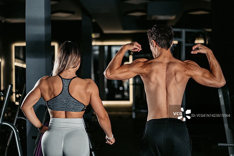 在健身房展示肌肉的年轻男人和女人图片素材