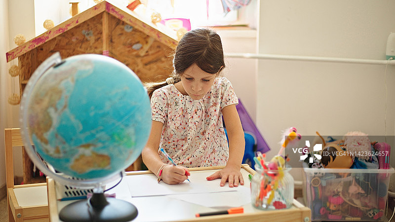 在书桌前画画的可爱小女孩图片素材
