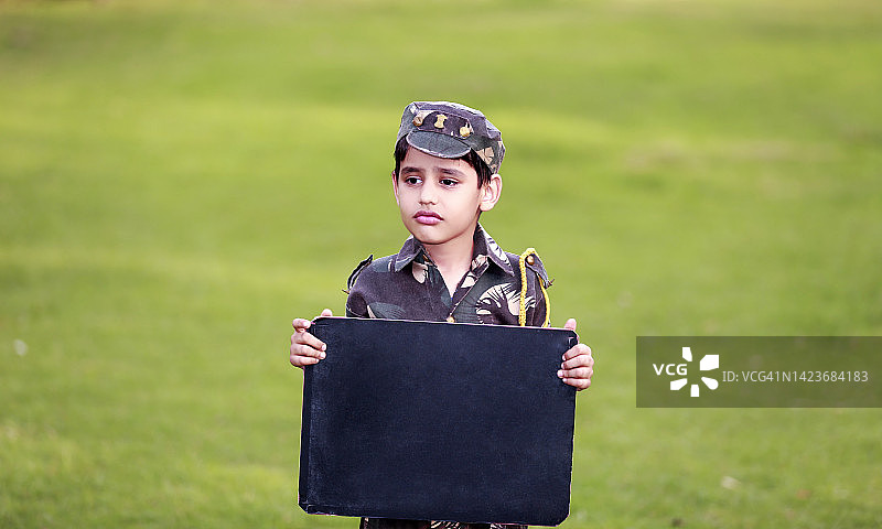 穿着军装、手拿黑板的儿童户外肖像图片素材