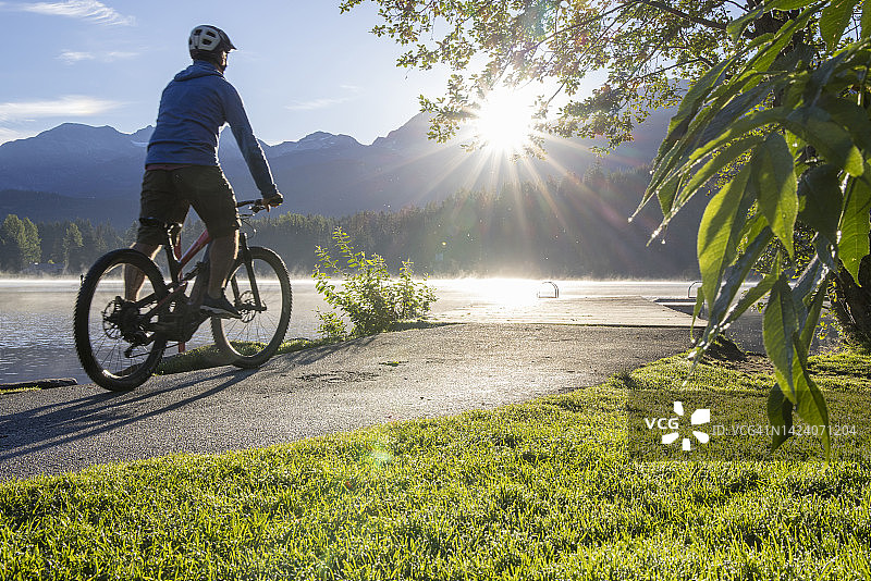 骑着电动山地自行车的年长者抵达日出时的湖边图片素材