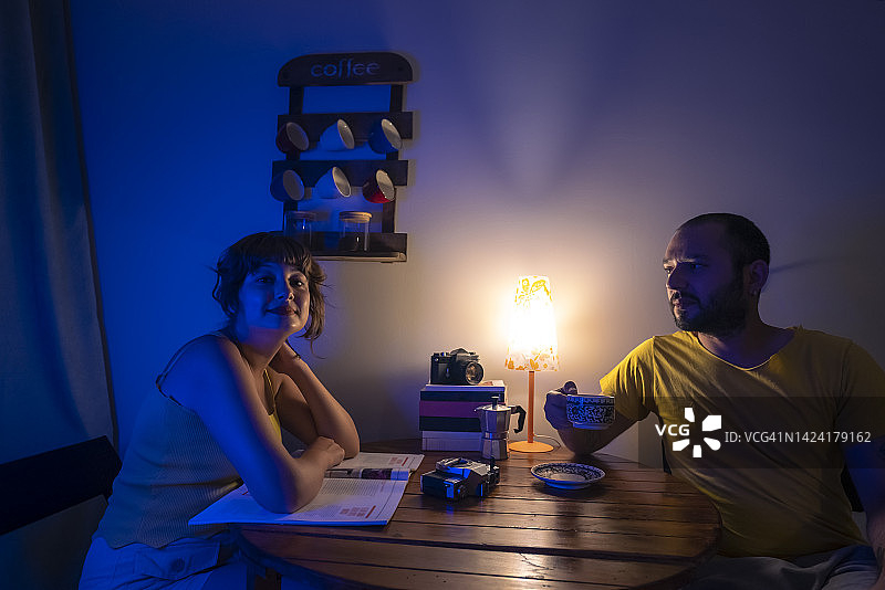 年轻夫妇坐在昏暗房间的桌旁图片素材