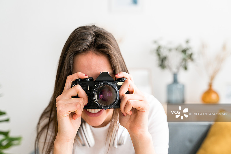 在室内手持专业相机微笑的女摄影师图片素材