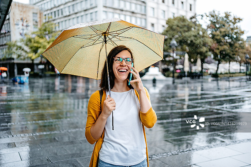 年轻女子在雨天户外打电话图片素材