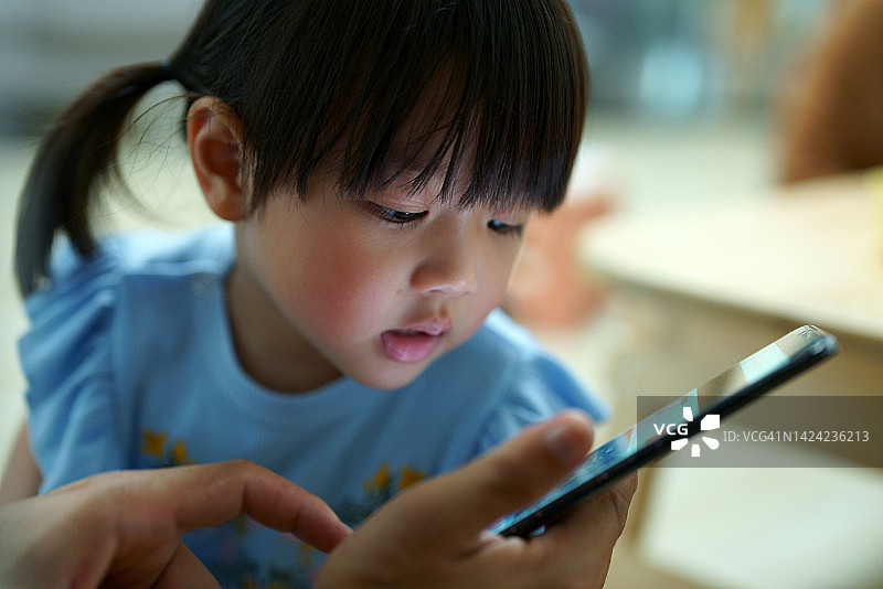 小女孩专注于手机屏幕图片素材