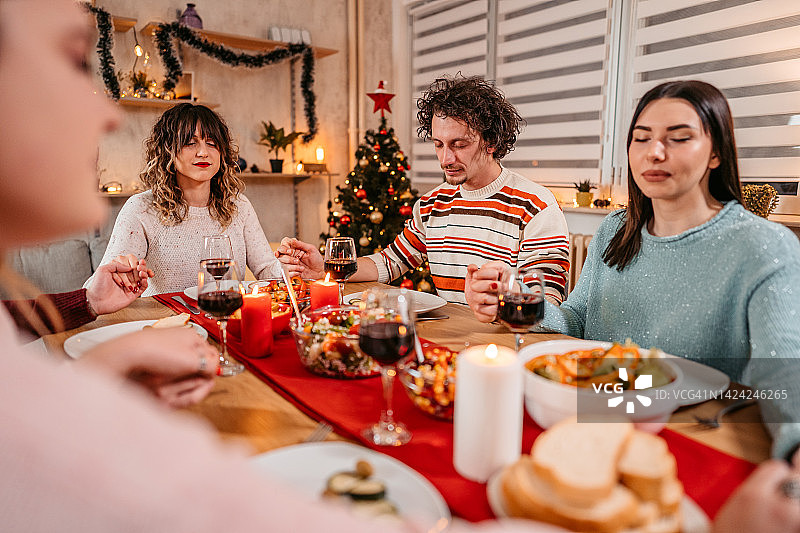 朋友们在圣诞晚餐上一起祈祷图片素材