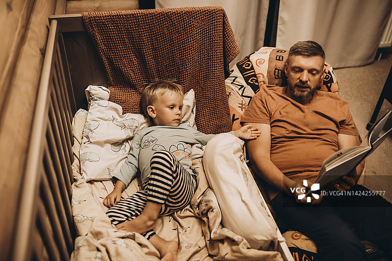 父亲在婴儿床里给儿子读图画书图片素材