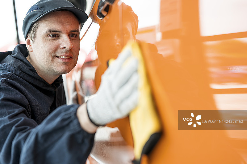 汽车外部精细服务：抛光和清洁，保持您的汽车价值。技术人员使用超细纤维布通过车身打蜡进行抛光和清洁图片素材