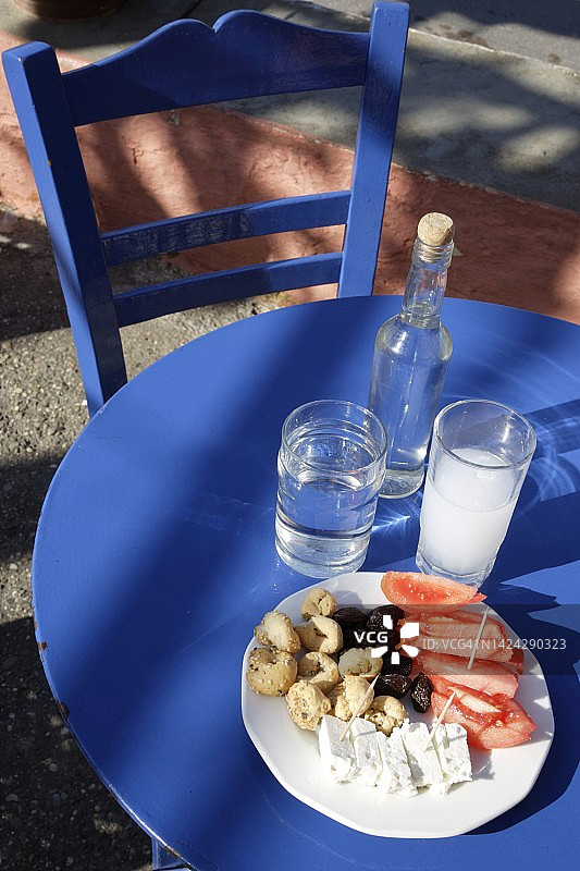 克里特岛小酒馆外的桌子，摆放着一杯和一瓶茴香酒以及梅泽图片素材