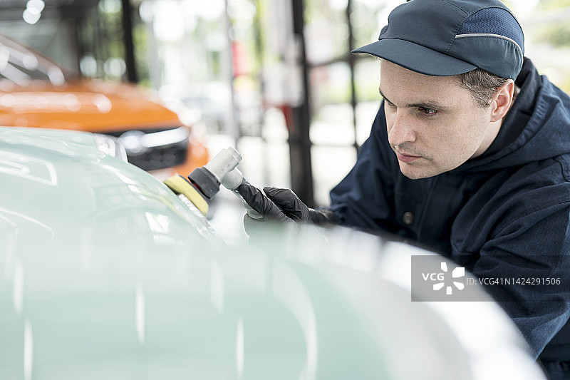 经典汽车维修、修理和翻新：汽车修理工在汽车保养服务中心修复和检查汽车保险杠的喷漆图片素材