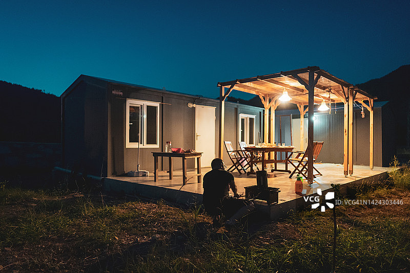 中年男人在集装箱房屋的后院准备烧烤晚餐图片素材