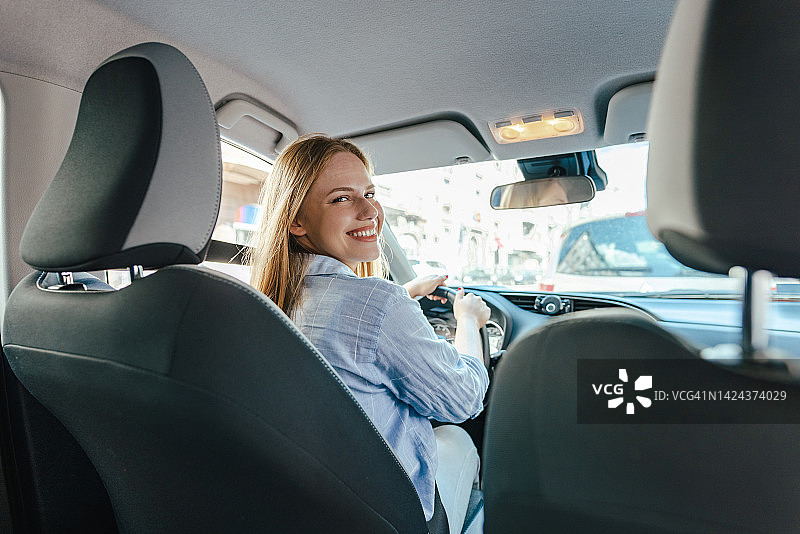坐在驾驶座上的年轻微笑女性图片素材